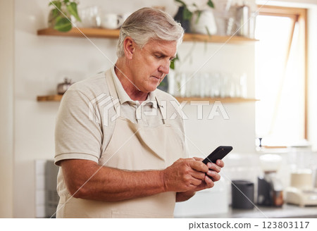 Typing, phone and senior man reading an email on a mobile app during retirement in his house. Elderly person with calm and peace while on the internet with a smartphone in the kitchen of his home Typing, phone and senior man reading an email on a mobile app during retirement in his house. Elderly person with calm and peace while on the internet with a smartphone in the kitchen of his home 123803117
