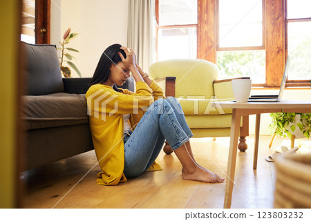 Stressed woman, depression and lonely in the living room sitting on the floor at home. Young sad female suffering from mental health issues and anxiety or headache in apartment or house 123803232