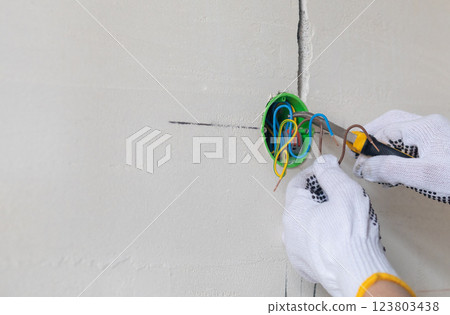 The master electrician connects the wires in the wiring box. The master electrician connects the wires in the wiring box. 123803438