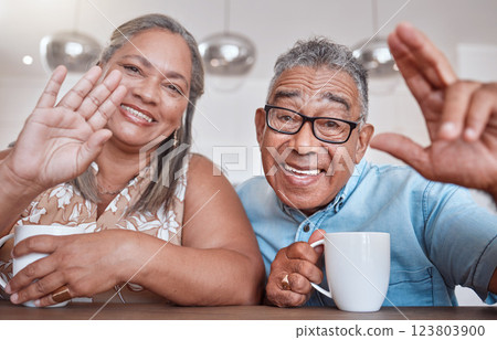 Senior couple, coffee and wave for video call smiling, talking or speaking at home. Elderly man and woman greeting on social media or face time while enjoying a warm beverage indoors 123803900