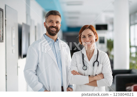 Portrait of two doctors in hospital hallway, holding medical records in hand. 123804021