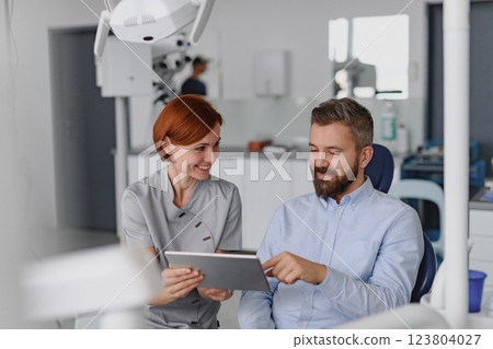 Female dentist showing x-ray to patient in dental clinic during anual check-up. Female dentist showing x-ray to patient in dental clinic during anual check-up. 123804027