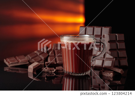 Hot chocolate and broken bitter chocolate bar on a black reflective background. 123804214