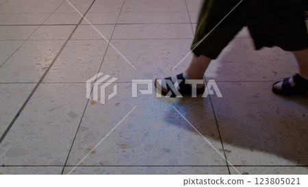 Closeup of person foot on a textured tile floor, highlighting the stylish outfit details and tile design Closeup of person foot on a textured tile floor, highlighting the stylish outfit details and tile design 123805021