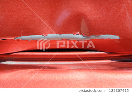 Close up of a red car with multiple visible scratches and paint damage The scratches expose the underlying metal, creating a contrast against the glossy surface. Perfect for automotive damage concepts Close up of a red car with multiple visible scratches and paint damage The scratches expose the underlying metal, creating a contrast against the glossy surface. Perfect for automotive damage concepts 123807415