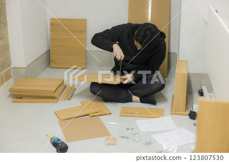 一名男子正在組裝有許多零件的家具 一名男子正在組裝有許多零件的家具 123807530