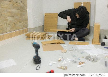 一名男子正在組裝有許多零件的家具 一名男子正在組裝有許多零件的家具 123807532