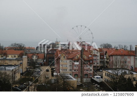 Enjoy a stunning view of the urban landscape with a Ferris wheel and rooftops Enjoy a stunning view of the urban landscape with a Ferris wheel and rooftops 123807600