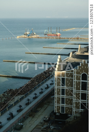 Lively Coastal Landscape Featuring a Pier Surrounded by a Diverse Crowd Lively Coastal Landscape Featuring a Pier Surrounded by a Diverse Crowd 123807618