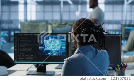 Engineer typing on computer in server hub, monitoring data center energy consumption using AI software. Technician inspecting rackmounts in server room using artificial intelligence tech, camera A 123807921
