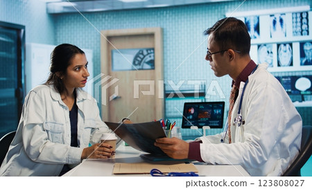 Physician meeting with a patient to discuss medical test results in a cabinet, using advanced diagnostic tools to interpret x ray scans, demonstrating a professional healthcare approach. Camera B. Physician meeting with a patient to discuss medical test results in a cabinet, using advanced diagnostic tools to interpret x ray scans, demonstrating a professional healthcare approach. Camera B. 123808027