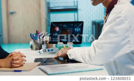 Physician meeting with patient to discuss medical test results in cabinet, using advanced diagnostic tools to interpret x ray scans, demonstrating a professional healthcare approach. Camera A. Physician meeting with patient to discuss medical test results in cabinet, using advanced diagnostic tools to interpret x ray scans, demonstrating a professional healthcare approach. Camera A. 123808031