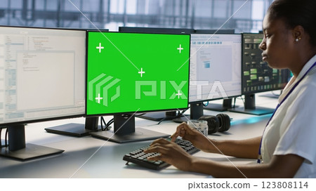 Data center technician using mockup PC, maintaining company network infrastructure. Server hub worker ensuring optimal system performance with green screen computer, camera A Data center technician using mockup PC, maintaining company network infrastructure. Server hub worker ensuring optimal system performance with green screen computer, camera A 123808114
