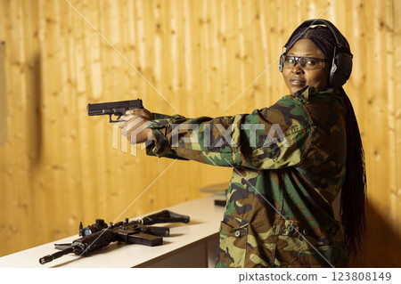 Portrait of woman soldier in shooting range doing training designed to increase safety and survivability in combat. Military unit practicing with pistol to increase handgun handling efficiency 123808149