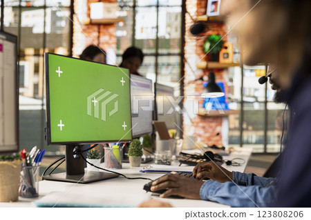 Call center agent wearing headset using green screen PC to resolve customers concerns, talking into mic. Customer service worker using headphones and chroma key computers to process clients orders Call center agent wearing headset using green screen PC to resolve customers concerns, talking into mic. Customer service worker using headphones and chroma key computers to process clients orders 123808206