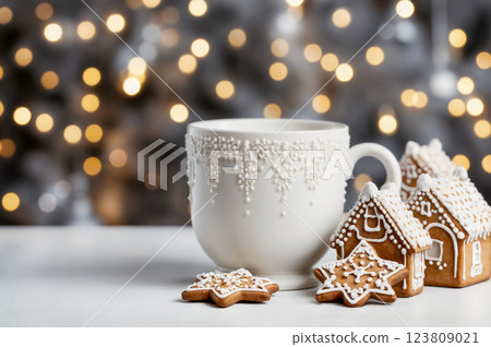 Gingerbread sweets with cup of milk, cacao or tea on blurred background with golden bokeh lights. Christmas and New Year holiday treats 123809021