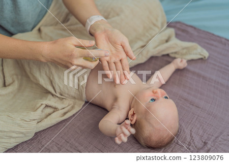 A mother gently massages her 1-month-old baby with baby oil after a bath. This tender moment highlights the bond between parent and child, promoting relaxation, baby care, and the importance of skin 123809076