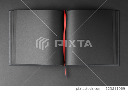 Open notebook with black sheets and red bookmark. 123811069