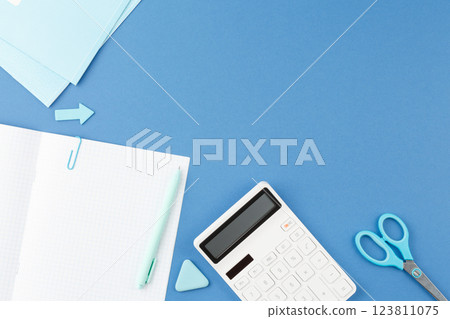 School notepad with study supplies on blue desk. 123811075