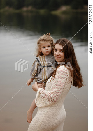 Caucasian mother holding baby standing on lake shore. 123812051