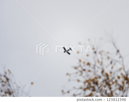 Small ultralight airplane with overhead wing and single propeller flying in sunset sky. 123812398