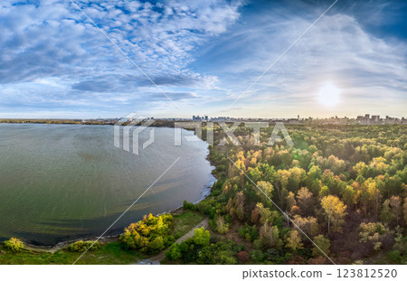 Autumn forest on lake shore at sunset and city on horizon, auerial view Autumn forest on lake shore at sunset and city on horizon, auerial view 123812520