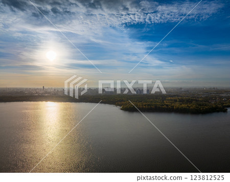 Autumn forest on lake shore at sunset and city on horizon, auerial view Autumn forest on lake shore at sunset and city on horizon, auerial view 123812525