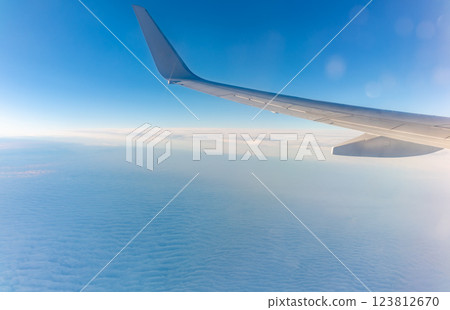 View from the airplane window at a beautiful cloudy sky and the airplane wing View from the airplane window at a beautiful cloudy sky and the airplane wing 123812670