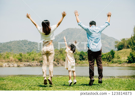 Asian family father mother and daughter jumping front lake with raised hands sunny day in park, lifestyle parents and child kid enjoying outdoors together in nature on summer travel, Family relaxation Asian family father mother and daughter jumping front lake with raised hands sunny day in park, lifestyle parents and child kid enjoying outdoors together in nature on summer travel, Family relaxation 123814873