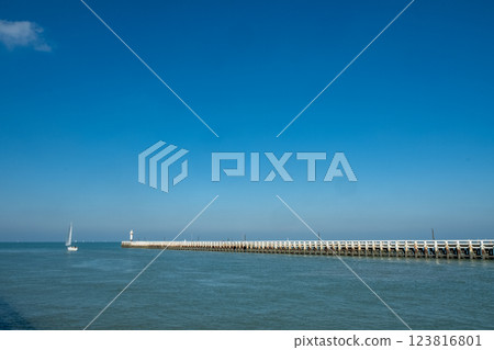 A serene seascape with sailboats gliding over calm waters under a clear blue sky 123816801