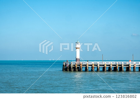A picturesque pier featuring a beautiful lighthouse against the backdrop of a calm sea A picturesque pier featuring a beautiful lighthouse against the backdrop of a calm sea 123816802