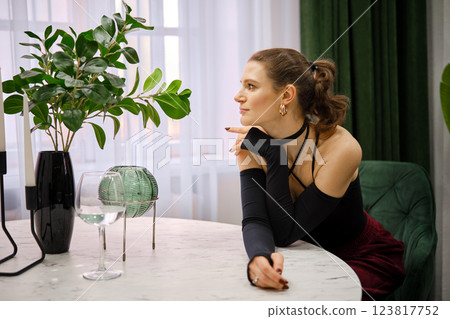 Elegant woman contemplating while seated at a stylish table in a modern indoor setting 123817752