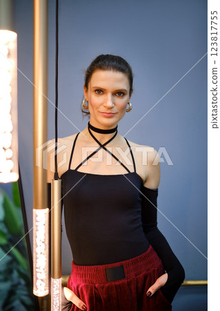 Stylish woman poses elegantly in black sleeveless top and red skirt at indoor location Stylish woman poses elegantly in black sleeveless top and red skirt at indoor location 123817755