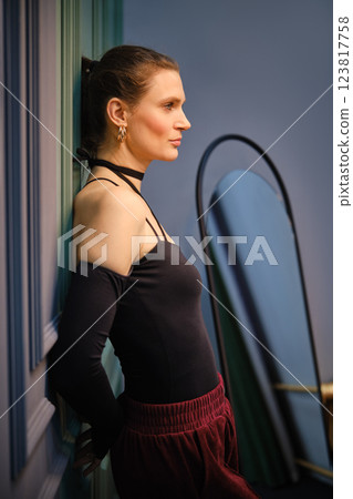 Elegant woman posing in a stylish room against a colorful wall at evening hours 123817758