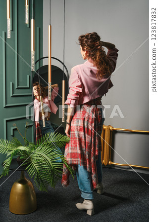 A stylish woman looks at herself in a full-length mirror 123817832