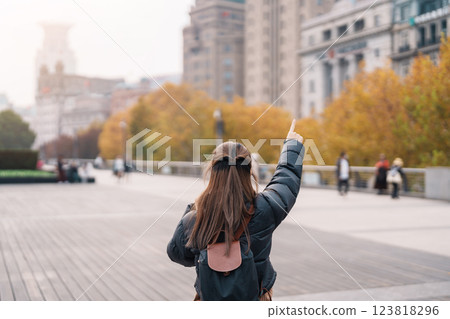 woman traveler visiting in Shanghai, China. Happy Female Tourist sightseeing Shanghai view in The Bund of Shanghai in Autumn season. landmark and popular for tourism attractions. Travel and Vacation 123818296