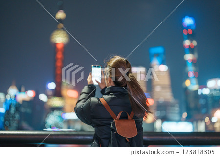 woman traveler visiting in Shanghai, China. Female Tourist with backpack sightseeing Shanghai view of Lujiazui in The Bund of Shanghai at night. landmark and popular for tourism attractions 123818305