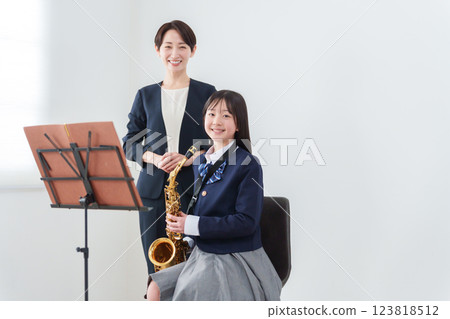 一位吹奏薩克斯風的銅管樂隊成員和一位女老師 123818512