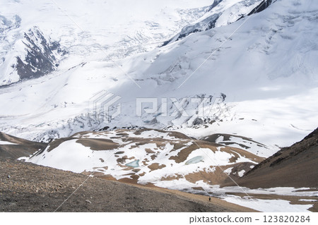 Wide shot of a solitary tiny hiker in a vast alpine glacier landscape, Pamir Mountains, Kyrgyzstan 123820284