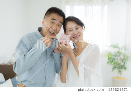 Senior couple in the living room holding a piggy bank 123821871