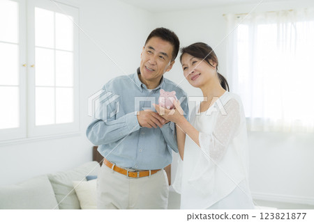 客廳裡拿著存錢筒的老年夫婦 客廳裡拿著存錢筒的老年夫婦 123821877