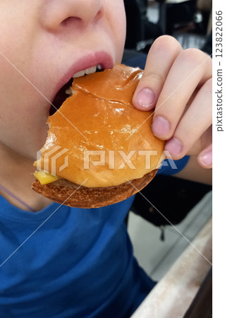 Boy bites into burger at fast food restaurant. Close-up 123822066