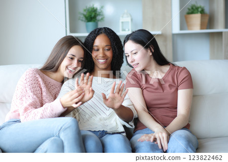 Three happy women looking at friend manicure at home Three happy women looking at friend manicure at home 123822462