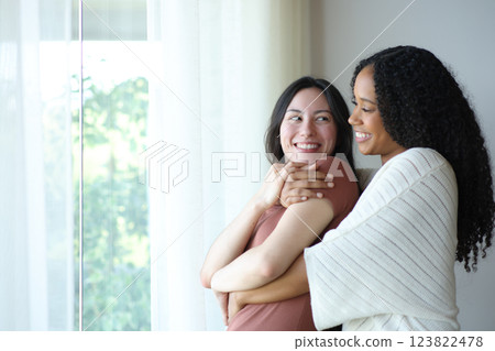 Happy interracial lesbian couple standing in love looking each other Happy interracial lesbian couple standing in love looking each other 123822478