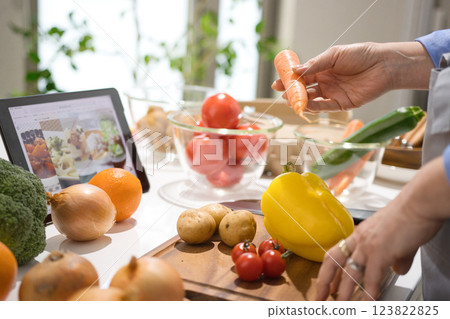 Middle woman cooking while looking at a tablet 123822825