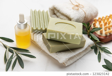 Natural olive oil soap, essential oil and white towels creating relaxing spa setting 123823142