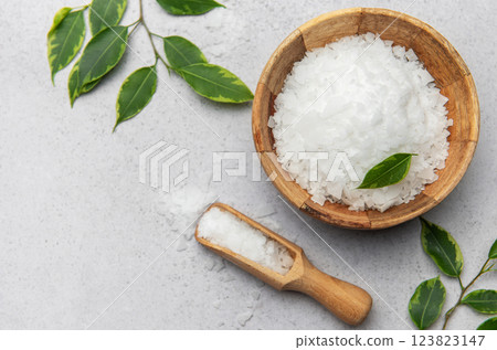 Magnesium flakes in wooden bowl with scoop and green leaves on gray background Magnesium flakes in wooden bowl with scoop and green leaves on gray background 123823147