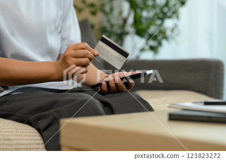 Close up of woman holding a credit card and making an online payment on smartphone Close up of woman holding a credit card and making an online payment on smartphone 123823272