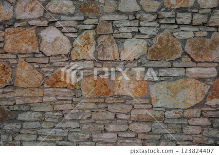 Unique stone wall featuring natural textures in Albania, showcasing a blend of smooth and rough stones with earthy tones 123824407