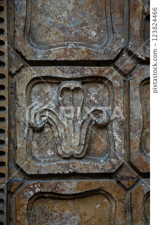 Detailed stone relief featuring a floral design, showcasing craftsmanship and historical architecture in an urban setting Detailed stone relief featuring a floral design, showcasing craftsmanship and historical architecture in an urban setting 123824466